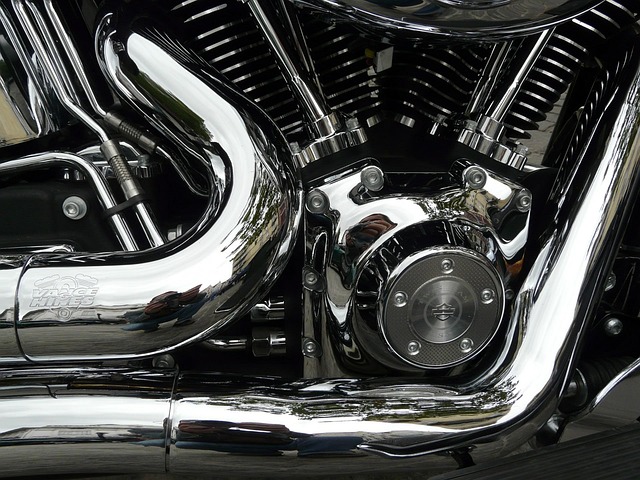 Close-up photo of a bike mechanic applying a single drop of lube to each roller of a clean bicycle chain while backpedaling.