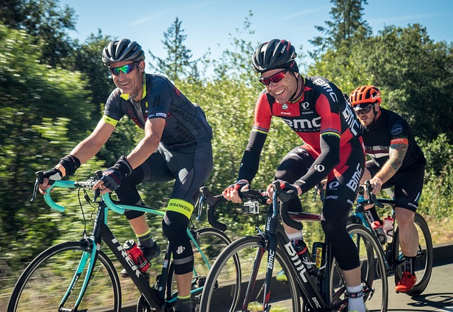 Three cyclists riding road bikes wearing cycling kits and helmets