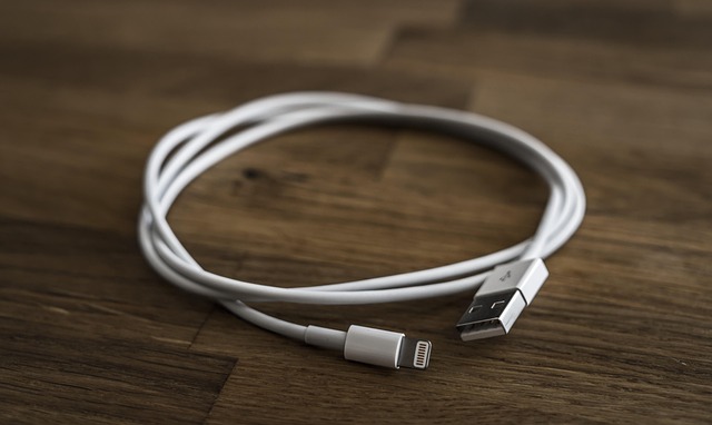A coiled white USB charging cable on a wooden surface