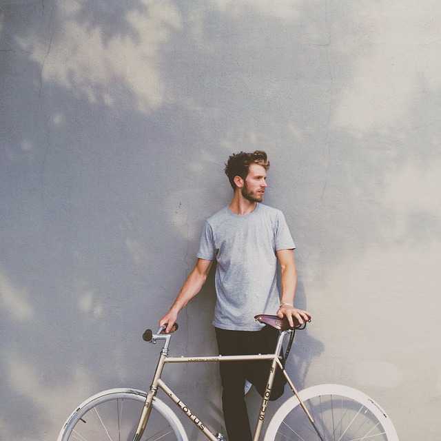 A man standing next to a bicycle against a wall