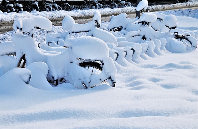 Bicycles parked outdoors completely covered in deep snow