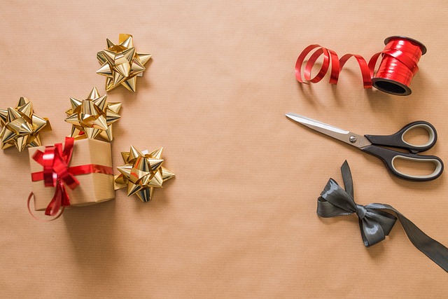 Gift wrapping supplies, scissors, ribbons, and a small present on craft paper